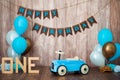 Blue retro toy car with helium balloons on a wooden background. Children`s holiday decorated photo zone for a little boy. Happy