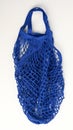 Blue reusable string bag woven from thread on white background