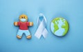 blue ribbon and gingerbread boy and planet earth on blue background. world day of fight against cancer Royalty Free Stock Photo