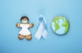 Blue ribbon and gingerbread girl and planet earth on blue background. world day of fight against cancer