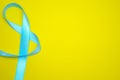 Blue ribbon in the shape of an eight. Yellow background. Copy space.