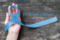 Blue ribbon symbolic of prostate cancer awareness campaign and men`s health in November month on hand support