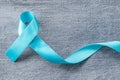 Blue ribbon symbolic of prostate cancer awareness campaign and men`s health in November month on Jeans denim