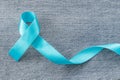 Blue ribbon symbolic of prostate cancer awareness campaign and men`s health in November month on Jeans denim