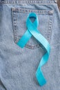 Blue ribbon symbolic of prostate cancer awareness and men`s health in November month on Jeans denim