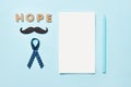 Blue ribbons with mustache, word hope and notepad with pen . Prostate Cancer Awareness. Men health awareness. Movember concept Royalty Free Stock Photo