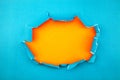 Blue ripped open paper on orange paper background Royalty Free Stock Photo
