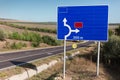 Blue road sign showing direction near highway. Royalty Free Stock Photo