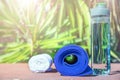 Blue Rolled Yoga Mat Bottle with Water White Towel on Greenery Palm Tree Nature Background. Bright Midday Sunlight. Relaxation
