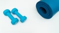 A blue rolled yoga mat and two blue dumbells 2 kg. Fitness equipment for home exercise and flexibility training. Royalty Free Stock Photo
