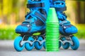 Blue roller skates with slalom cones lying on asphalt.