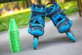 Blue roller skates with slalom cones lying on asphalt.