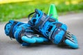 Blue roller skates with slalom cones lying on asphalt.