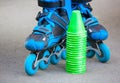 Blue roller skates with slalom cones lying on asphalt.