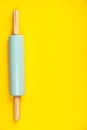 Blue rolling pin on yellow background, flat lay