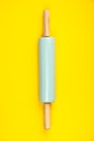 Blue rolling pin on yellow background, flat lay