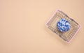 A blue rope ball lies in a miniature shopping basket on a beige background, top view