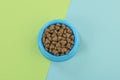 Blue round feeding bowl with dark brown heart shaped pet kibble