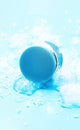 Blue round plastic container with cosmetic substances, captured on solid light-blue background with ice cubes Royalty Free Stock Photo