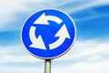 Blue roundabout crossroad road traffic sign against blue sky