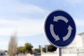 Blue roundabout sign with white arrows clockwise