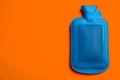 Blue rubber hot water bottle on orange background, top view. Space for text Royalty Free Stock Photo