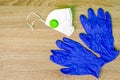 Blue rubber medical gloves and respirator mask lie on wooden table. Concept of hygiene and protection of human from bacteria. Copy