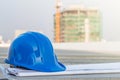 The blue safety helmet and the blueprint at construction site with crane background Royalty Free Stock Photo