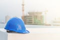 The blue safety helmet and the blueprint at construction site with crane background Royalty Free Stock Photo