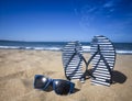 Blue sandal flip flop and sunglasses on the sand beach with blue sea and sky background in summer vacations. Copy space Royalty Free Stock Photo