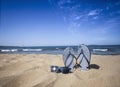 Blue sandal flip flop and sunglasses on the sand beach with blue sea and sky background in summer vacations. Copy space Royalty Free Stock Photo