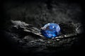 Blue sapphire on black coal background Royalty Free Stock Photo