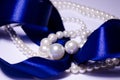 Blue satin ribbon with pearl jewelry. Luxurious decoration. For jewelry sites, blogs about fashion, style, jewelry. Snow-white