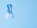 Blue satin Ribbon symbol of prostate cancer awareness on a bright blue background. Concept of medicine and health care Royalty Free Stock Photo