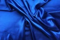 Blue satin, silky fabric, wave, draperies. Beautiful textile backdrop. Close-up. Top view