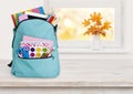 Blue school backpack on wooden table over autumn windowsill background Royalty Free Stock Photo