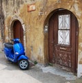 Blue Scooter Over Old Wall