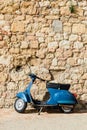 Blue scooter by the stone wall in an old town in Tuscany Royalty Free Stock Photo