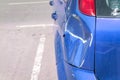 Blue scratched car with damaged paint in crash accident or parking lot and dented damage of metal body from collision Royalty Free Stock Photo