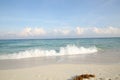 Blue sea with foam wave, white sand with footprints on the beach and blue sky with clouds on the horizon Royalty Free Stock Photo