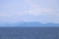 Blue sea with mountains and sky as background. Royalty Free Stock Photo