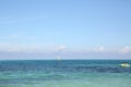 Blue sea with sailboat and boat with people and blue sky with clouds on the horizon