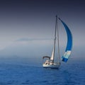 Blue sea with sailboat sailing in a foggy coast