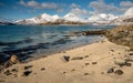 Blue sea, sand beach and snowy mountains during a sunny day. Royalty Free Stock Photo