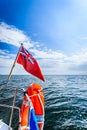 Blue sea. View from deck of yacht sailboat british flag lifebuoy. Travel.