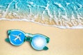 Blue sea wave, sand beach, turquoise ocean water, sunglasses, mirror reflection of airplane flight and shiny sun in sky top view Royalty Free Stock Photo