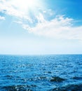 blue sea with waves and sky with sun and clouds Royalty Free Stock Photo