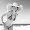 Smiling modern woman in bikini and beach straw hat on seacoast