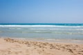 Blue sea with white waves and sand with footprints