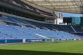 Blue Seatings, Green Pitch, Gallery and Glass Benches inside Empty Stadium Before Soccer Match